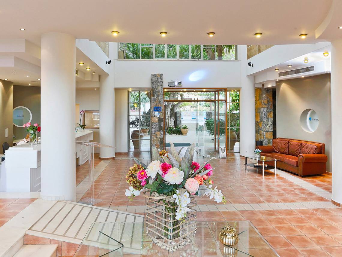 Empfangsbereich des Blue Sea Beach Affiliated by Melia Hotels mit Blumenarrangement und Sofa.