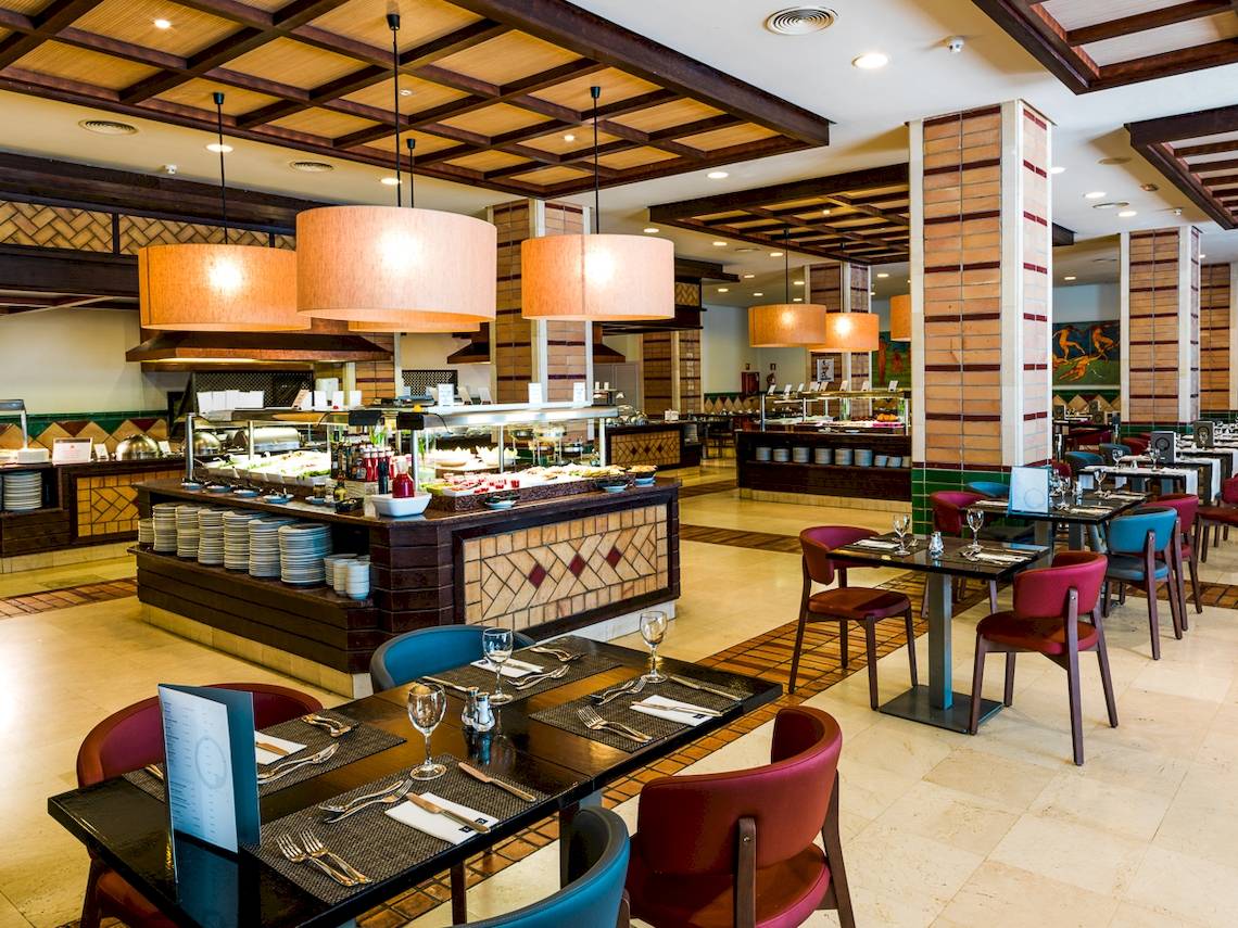 Innenansicht des Restaurants im H10 Estepona Palace mit Buffet und gedeckten Tischen.