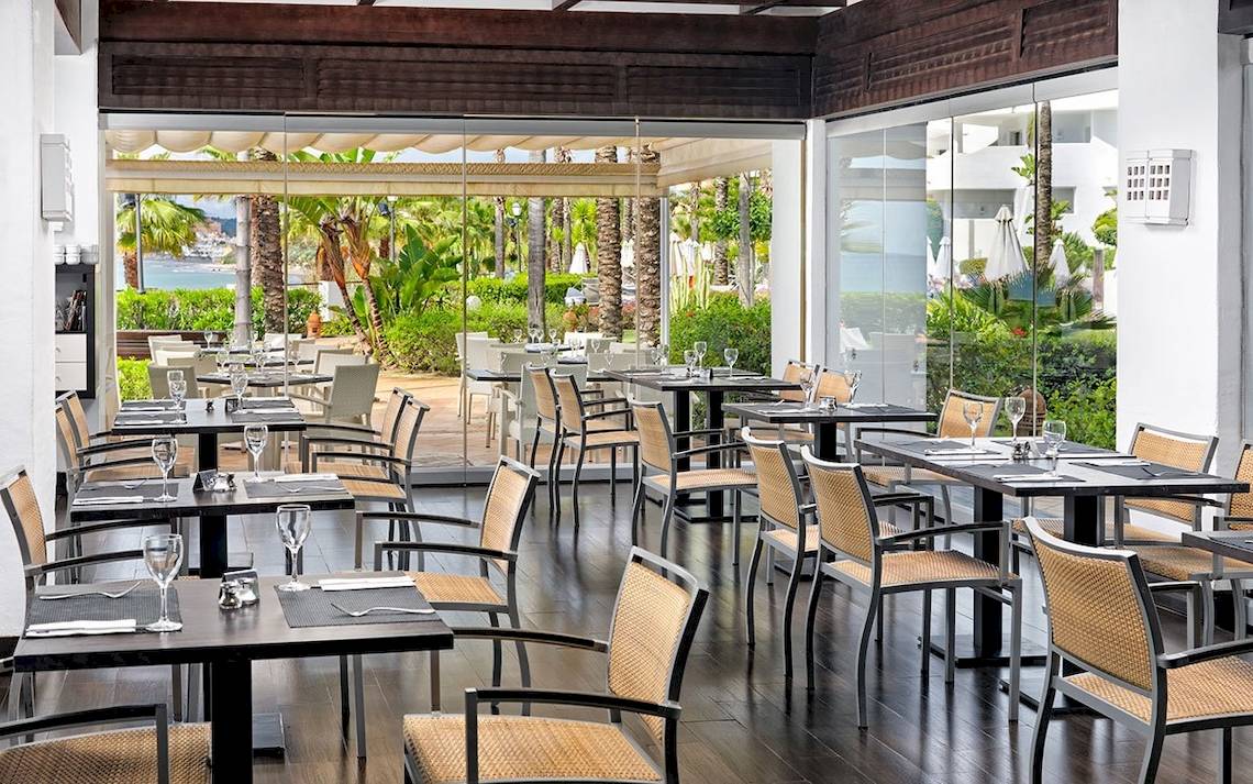 Innenansicht des Restaurants im H10 Estepona Palace mit Blick auf den Garten und das Meer.