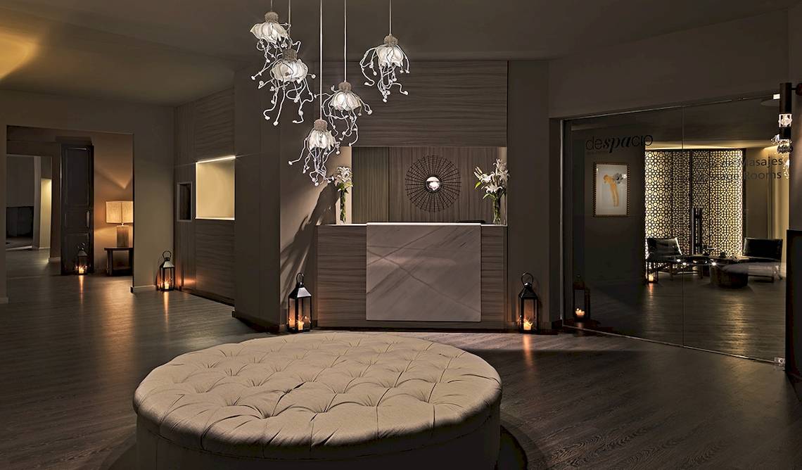 Empfangshalle des H10 Estepona Palace mit modernen Lampen und einem großen Sofa.