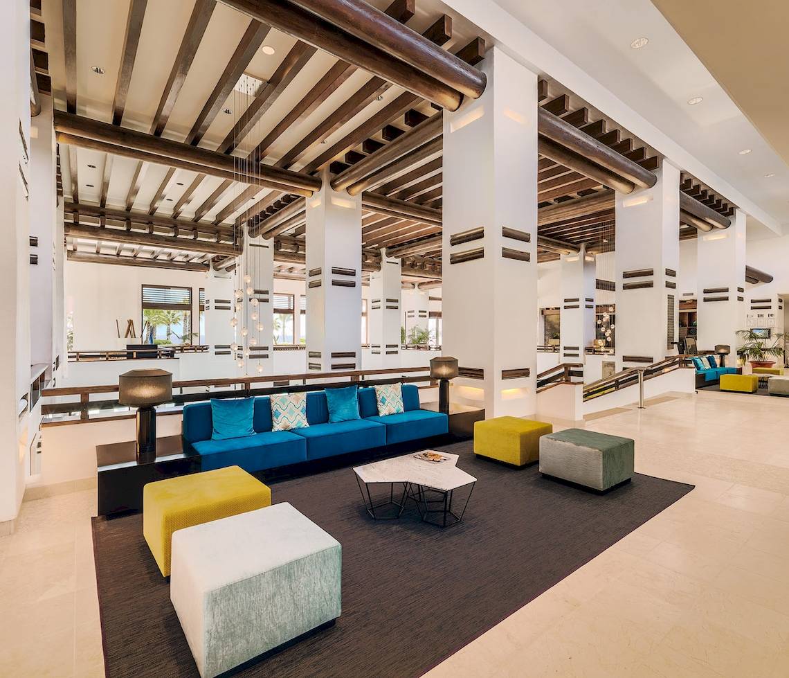 Innenansicht des H10 Estepona Palace Lobbys mit blauem Sofa und gelben Hockern.