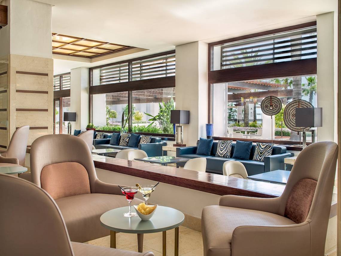 Lobby-Lounge-Bereich des H10 Estepona Palace mit modernen Möbeln und großen Fenstern.