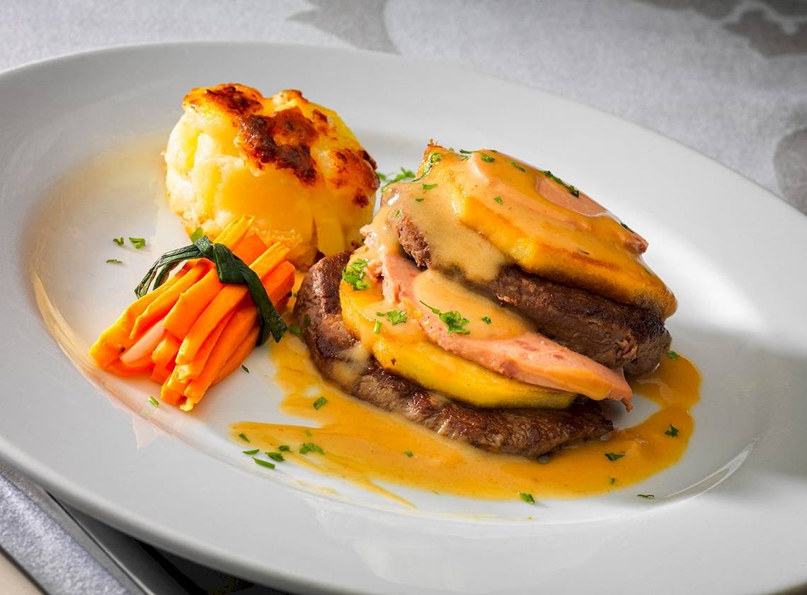 Ein Gericht auf einem weißen Teller, bestehend aus Steak, Kartoffelpüree und Karotten.