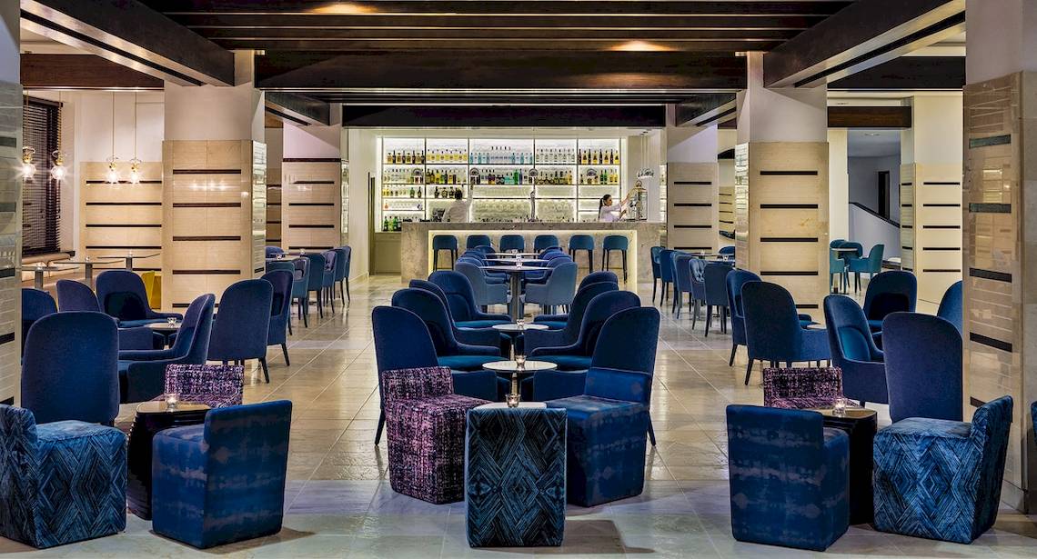 Innenbereich des H10 Estepona Palace Hotels mit Bar und blauen Stühlen.
