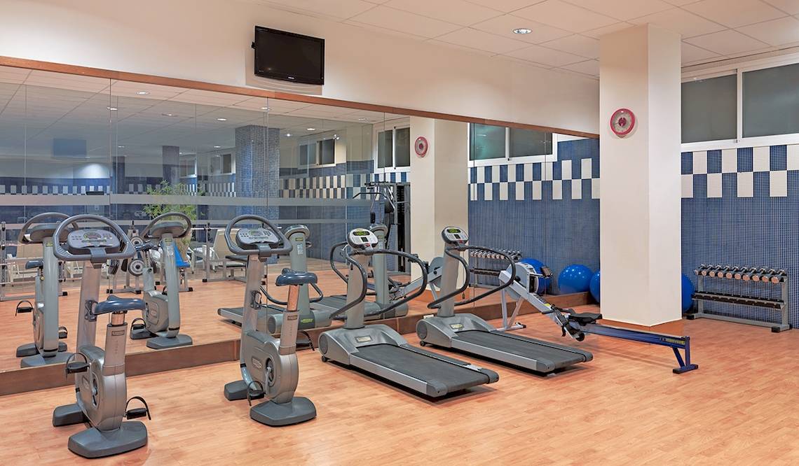Fitnesscenter im H10 Estepona Palace mit Laufbändern, Rudergeräten und Hanteln.