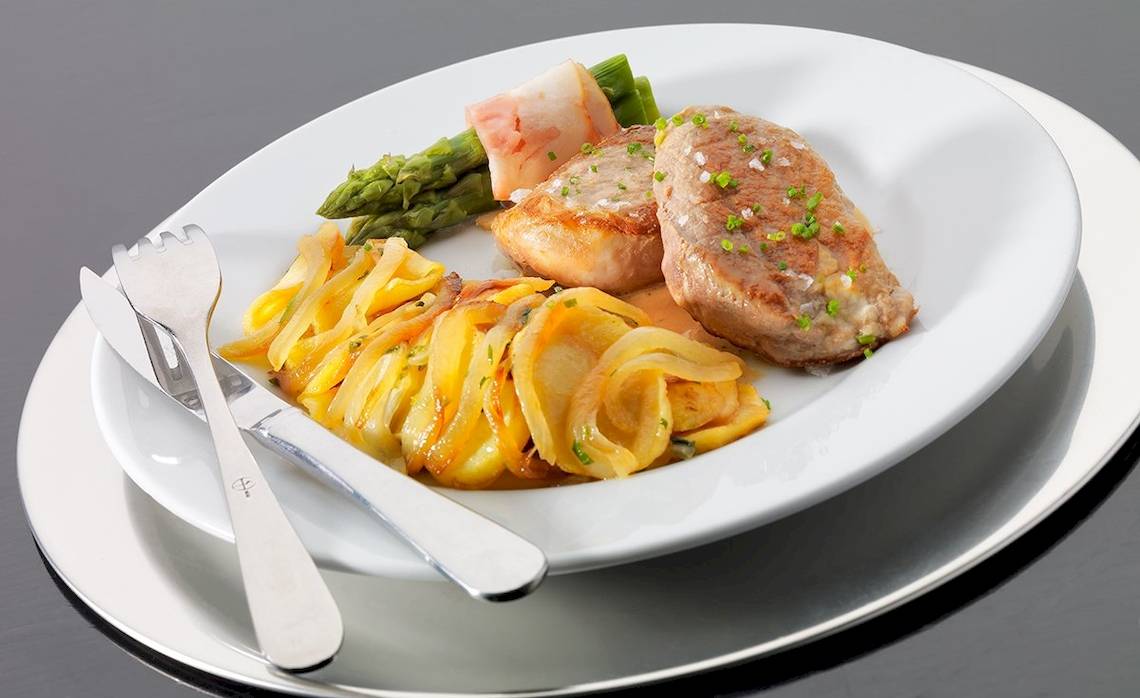 Gericht auf einem weißen Teller im H10 Estepona Palast Hotel mit Fleisch, Gemüse und Beilagen.