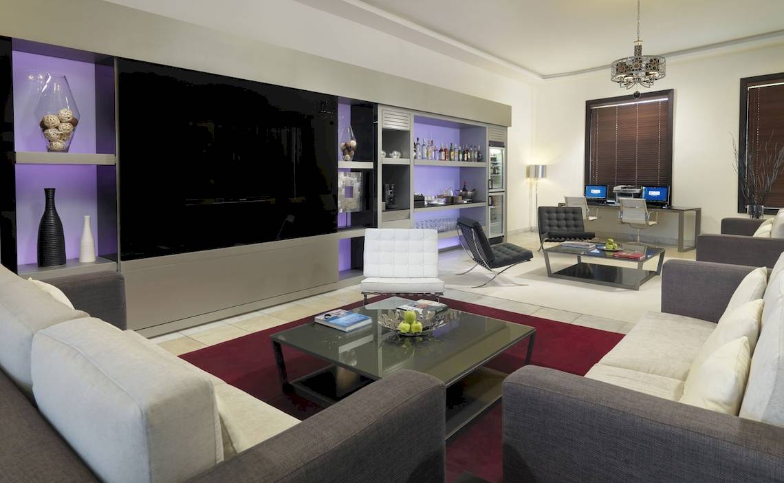 Modernes Wohnzimmer im H10 Estepona Palast mit großen Sofas, Tisch, Fernseher und Dekor.