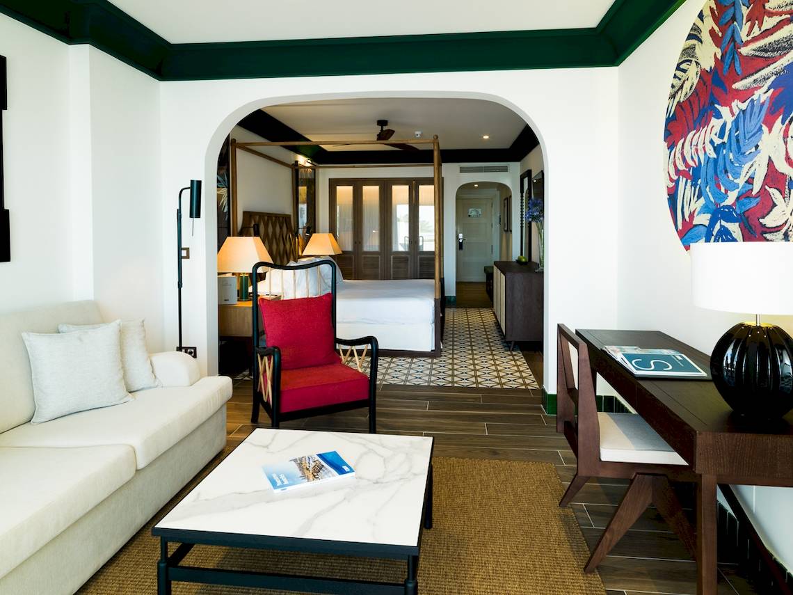 Innenraum der Suite im H10 Estepona Palace mit Wohnzimmer, Esstisch, Schlafzimmer und Dekoration.