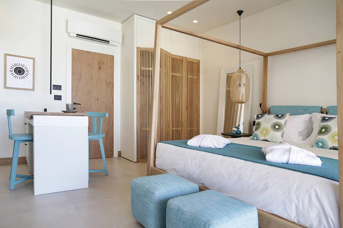 Schlafzimmer im Domes Noruz Chania mit Himmelbett, Blautönen und modernem Design.