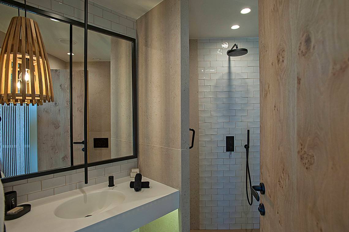 Badezimmer im Domes Noruz Chania, Autograph Collection mit Spiegel, Waschbecken und Duschbereich.