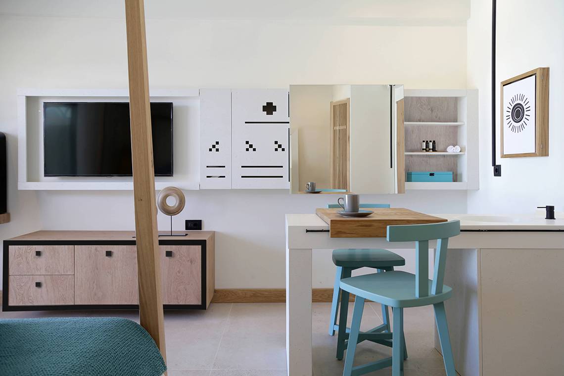 Innenansicht der Suite im Domes Noruz Chania, Autograph Collection mit Fernseher, Essbereich und offenem Badezimmer.