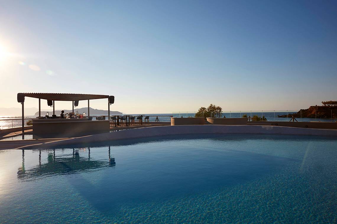 Pool-Ansicht des Domes Noruz Chania, Autograph Collection mit Bar und Blick auf das Meer.
