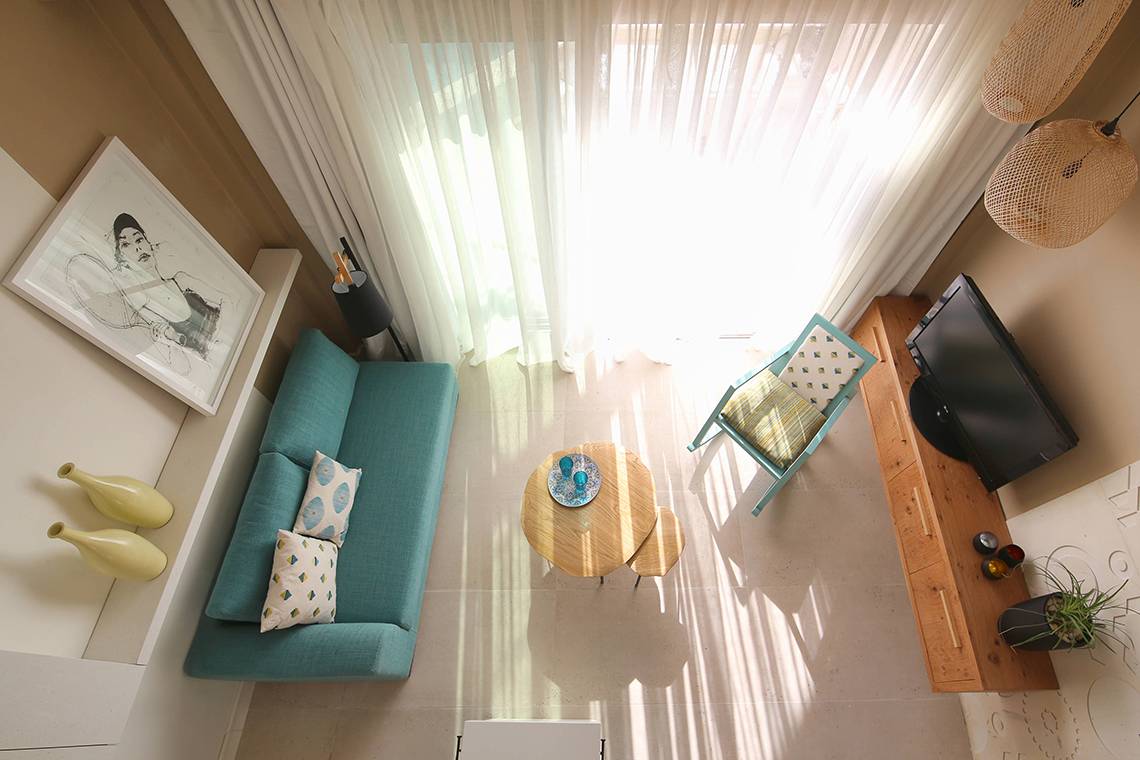 Luftaufnahme des Wohnzimmers im Hotel Domes Noruz Chania mit grünem Sofa, Tisch und Fernseher