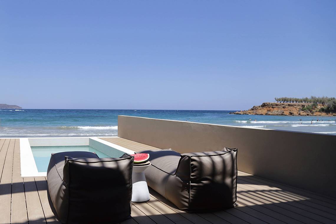 Terrasse des Domes Noruz Chania, Autograph Collection, mit Blick auf das Meer und gefüllt mit Loungesesseln und einem kleinen Pool.