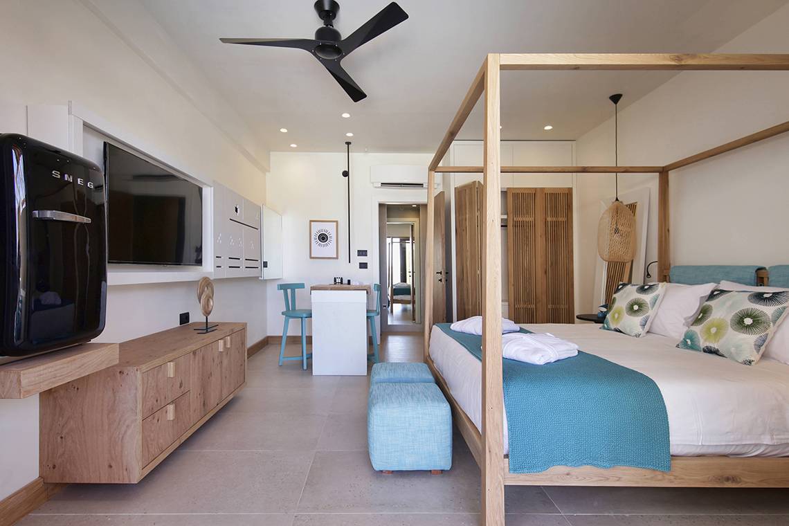 Schlafzimmer im Domes Noruz Chania mit vierposterbett, Fernseher, und modernem Interieur.