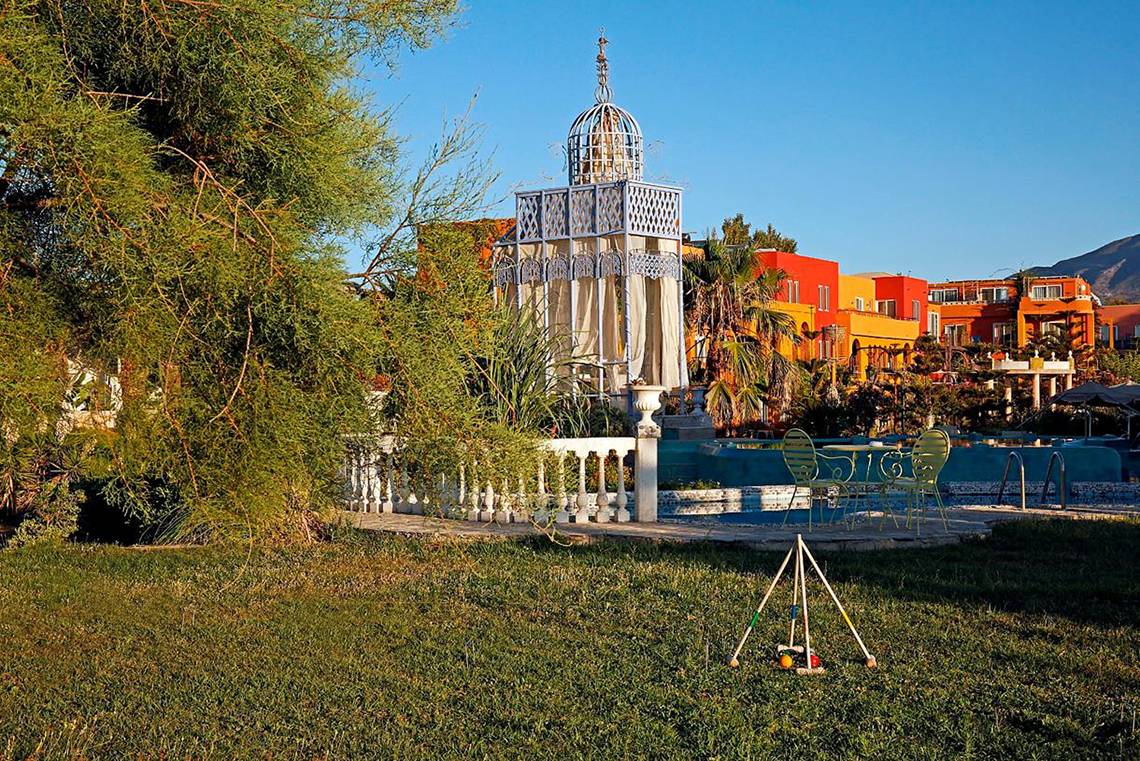 Außenbereich des Orpheas Resorts mit Garten, Spielgeräten und bunten Gebäuden im Hintergrund.