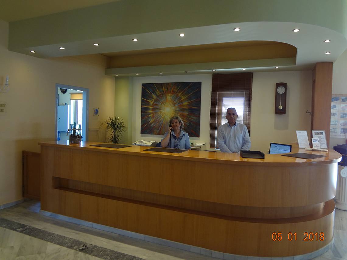 Rezeption des Europa Beach Hotel & Spa mit zwei Mitarbeitern, eines telefoniert, im Hintergrund eine große Wandmalerei.