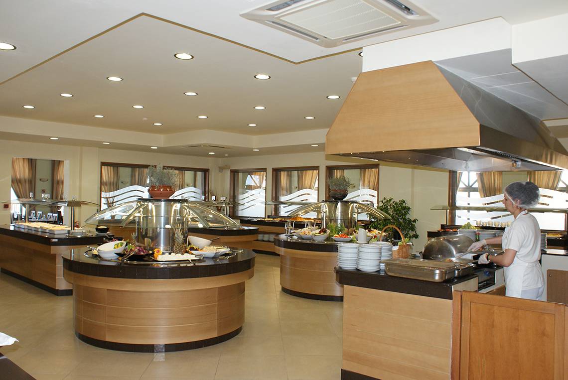 Buffet im Restaurant des Europa Beach Hotel & Spa mit verschiedenen Speisen, serviert von einer Angestellten.