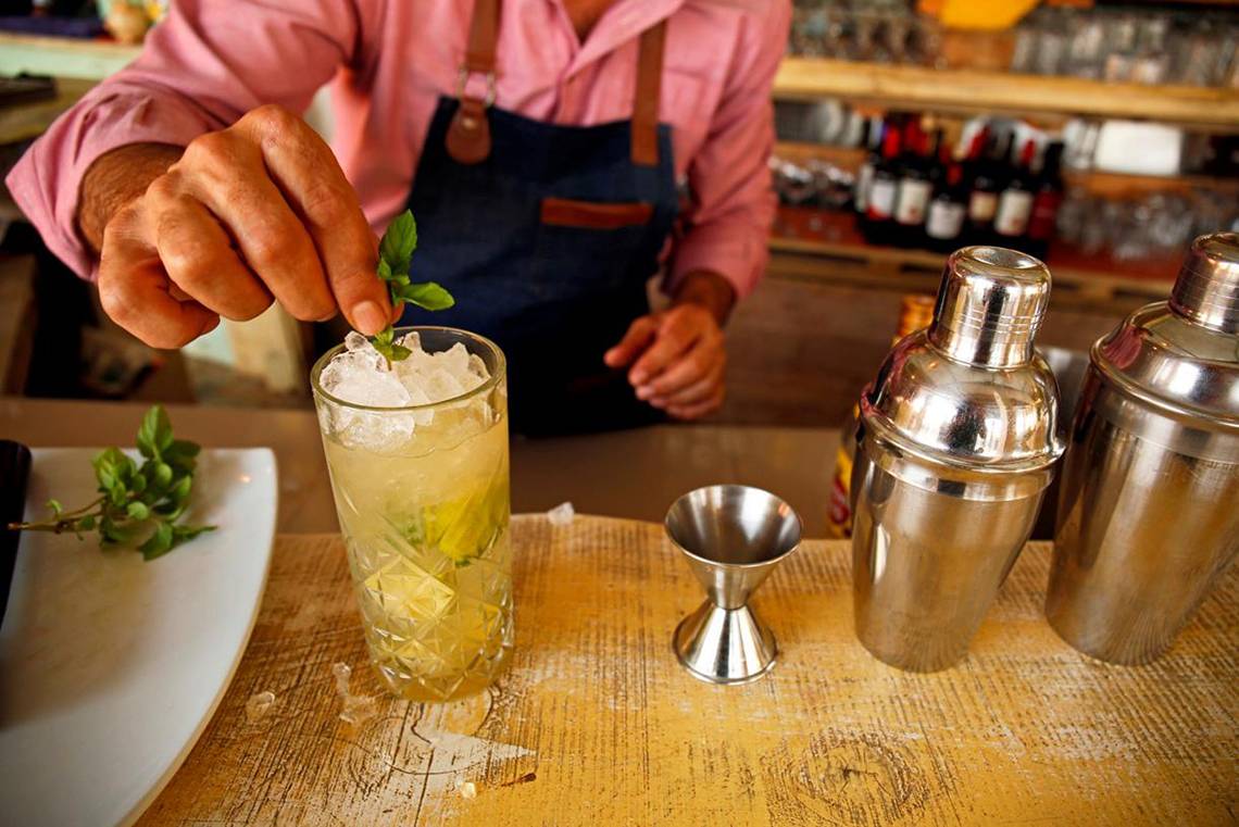 Ein Barkeeper bereitet einen Cocktail im Orpheas Resort zu, mit einem Glas auf einem Tisch, umgeben von Shakern.