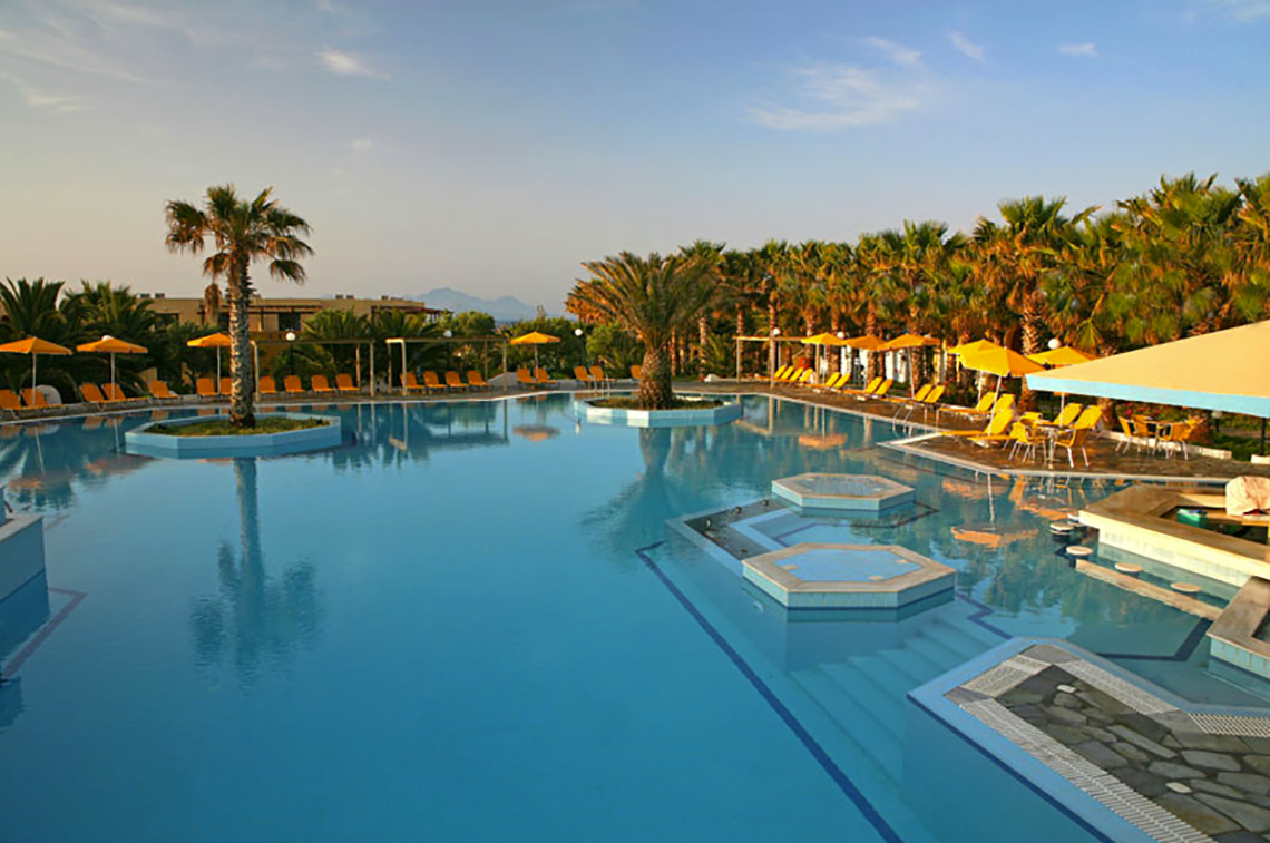 Außenpool des Porto Bello Beach Hotels mit Sonnenliegen und Palmen
