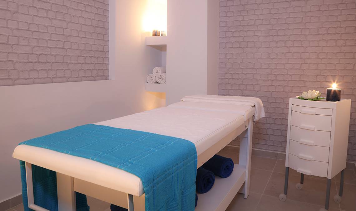 Behandlungsraum im LABRANDA Marine Aquapark Spa mit weißen Wänden, Ziegelmuster und blauen Handtüchern.
