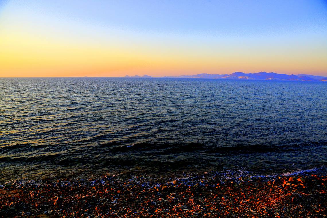 Abendlicher Meerblick mit Felsstrand und ruhigen Wellen am Horizont