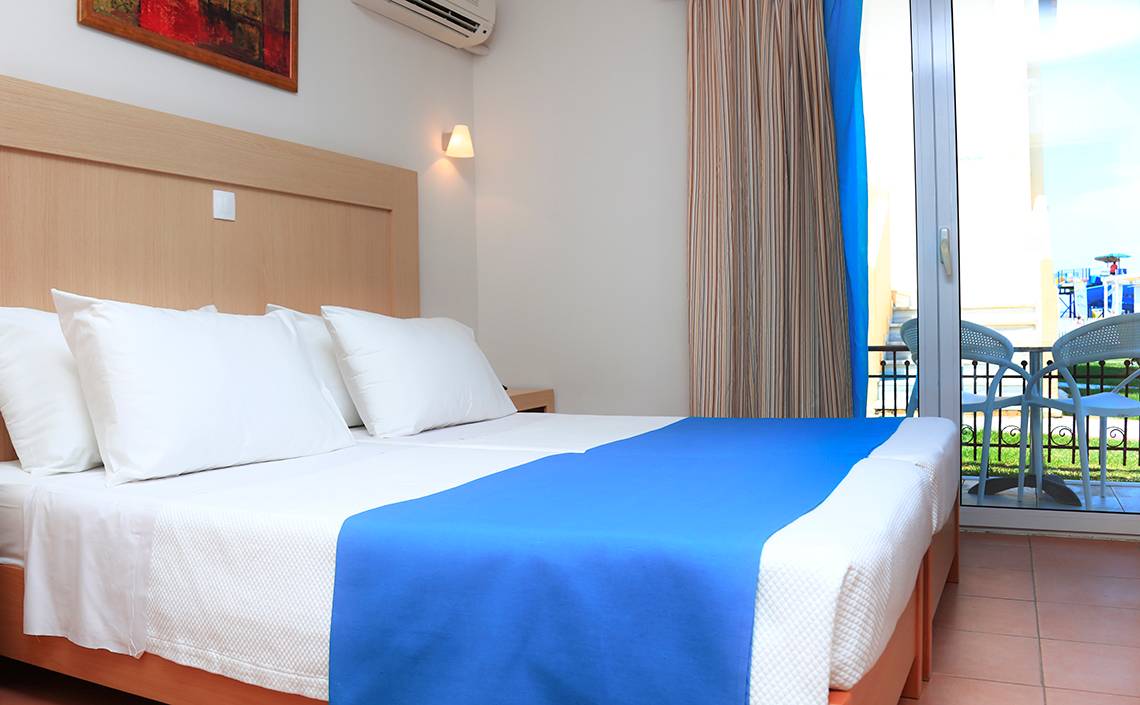 Foto eines Hotelzimmers im LABRANDA Marine Aquapark mit zwei Betten, weißen Kissen und einem Balkon.