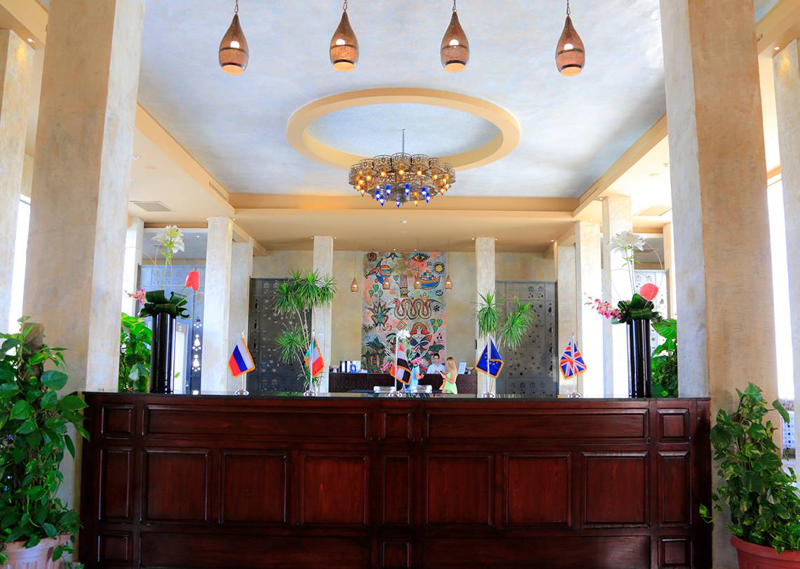 Empfangshalle des Sharm Club Beach Resorts mit hohen Säulen, Kronleuchter und Flaggen.