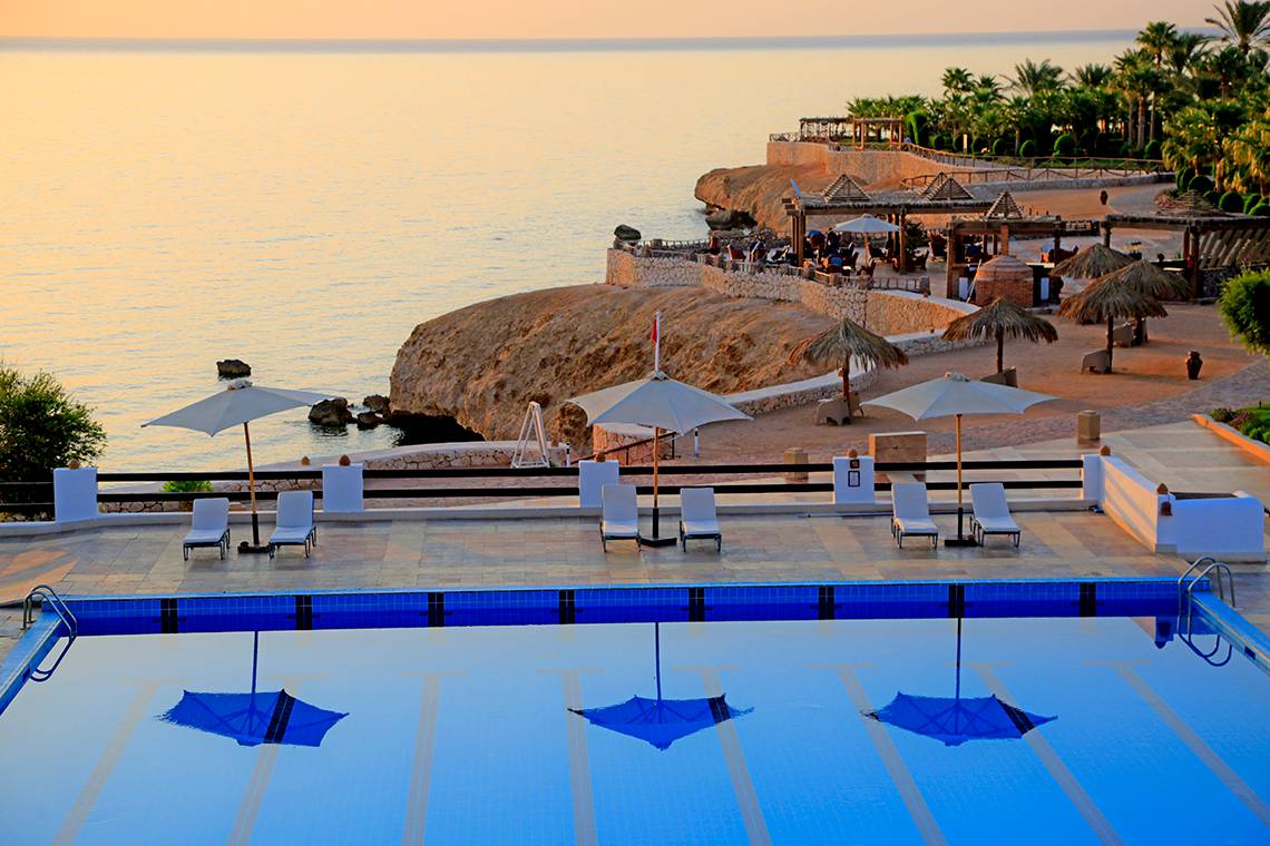 Sharm Club Beach Resort Pool bei Sonnenuntergang mit Blick auf das Meer und Loungestühlen