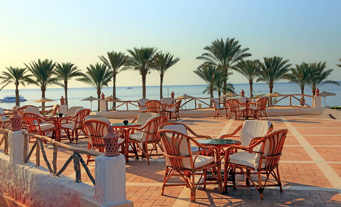 Außenterrasse des Sharm Club Beach Resorts mit Blick auf das Meer und Palmen