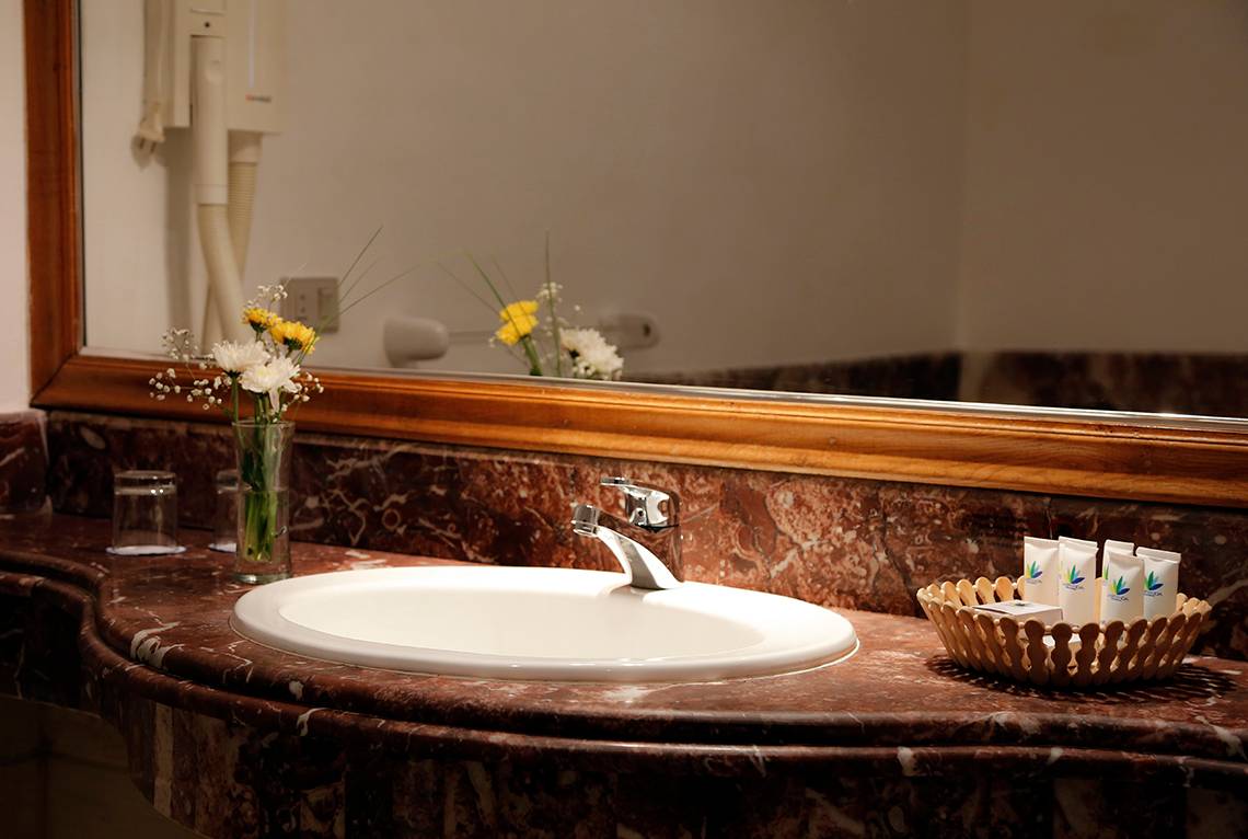Badezimmer im Sharm Club Beach Resort mit einem Waschbecken, Spiegel und Blumen