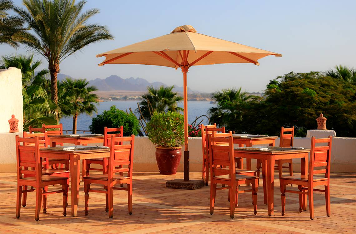 Terrasse im Sharm Club Beach Resort mit Tischen und Stühlen und Blick aufs Meer