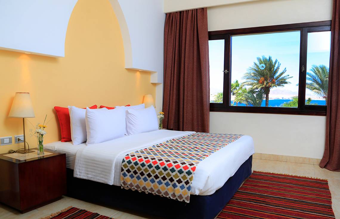 Ein Zimmer im Sharm Club Beach Resort mit Blick auf das Meer und Palmen.