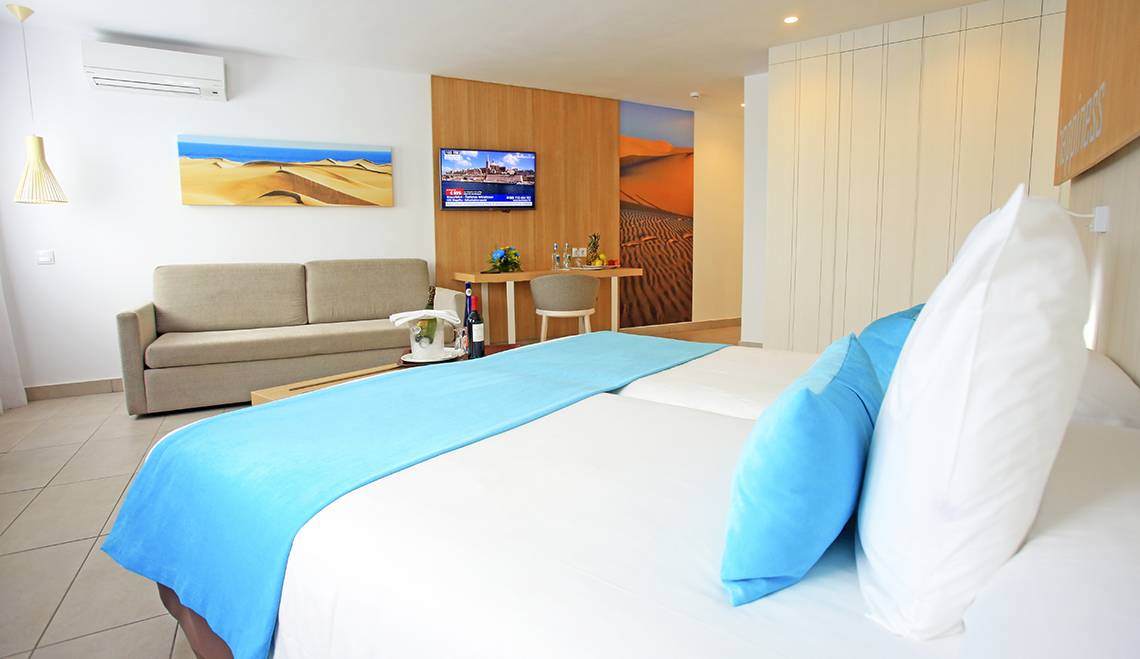Hotelzimmer im LABRANDA Playa Bonita mit zwei Betten, Sofa, Fernseher und Dekoartikeln.