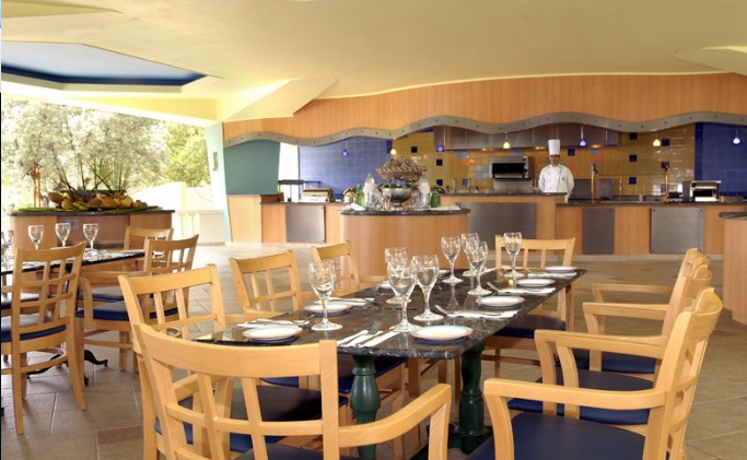 Innenansicht des Restaurants im Dreams Curacao Resort, Spa & Casino mit gedecktem Tisch und Kochbereich.