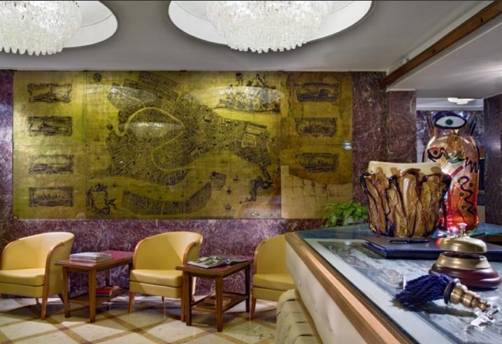 Innenansicht der Lobby des Montecarlo Hotels mit gelben Stühlen, Tischen und einer großen Wandkarte.