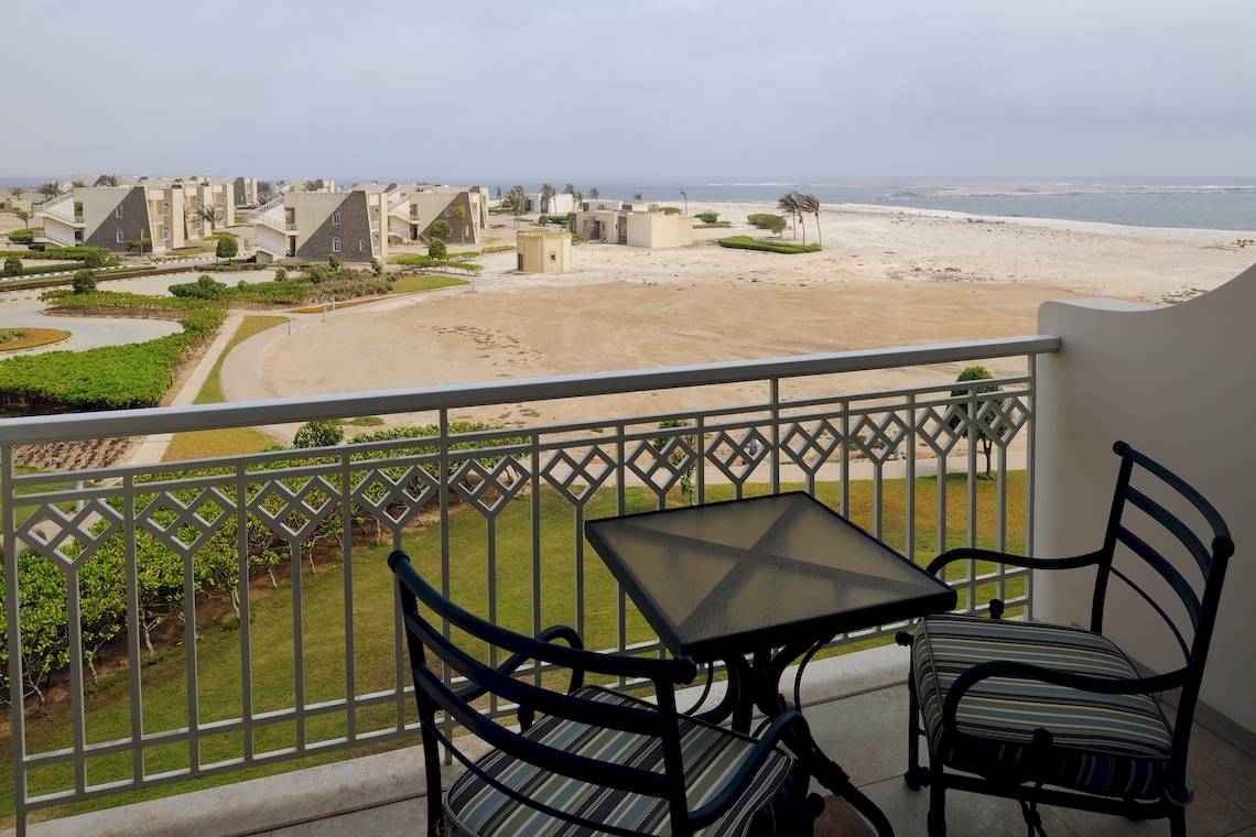 Blick vom Balkon des Wyndham Garden Salalah Mirbat auf eine weite Wüste und das Meer.