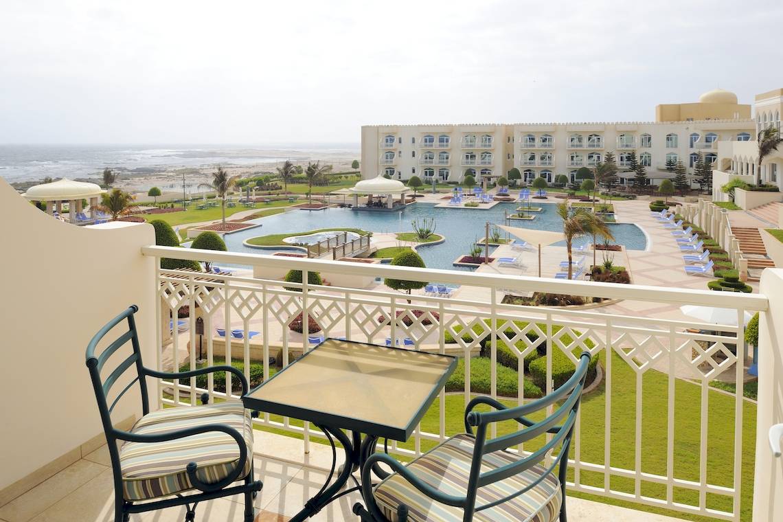 Aussicht vom Balkon des Wyndham Garden Salalah Mirbat Hotels auf den Swimmingpool und das Meer.