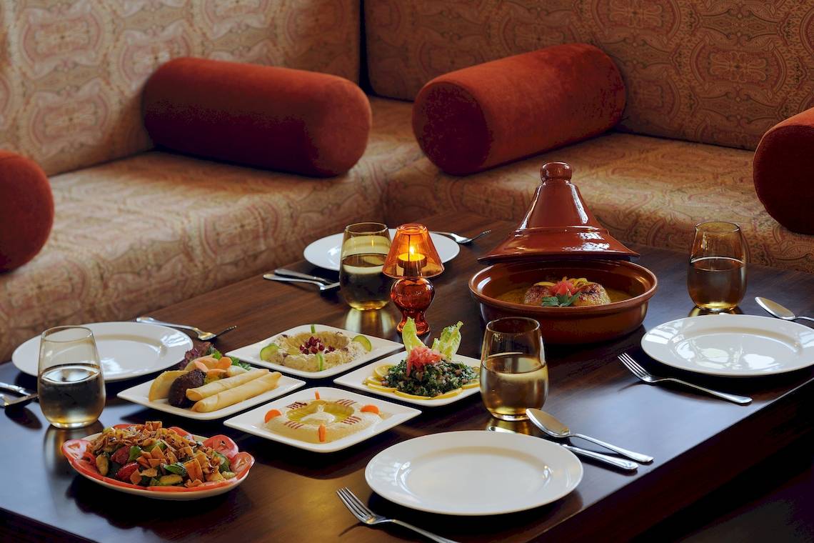 Ein Tisch im Restaurant des Wyndham Garden Salalah Mirbat mit verschiedenen Gerichten und Gläsern.