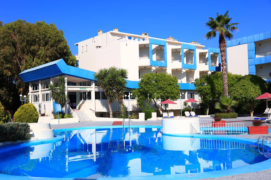 Das Blue Bay Beach Resort mit einem blauen Swimmingpool und weißen Gebäuden vor einem blauen Himmel.