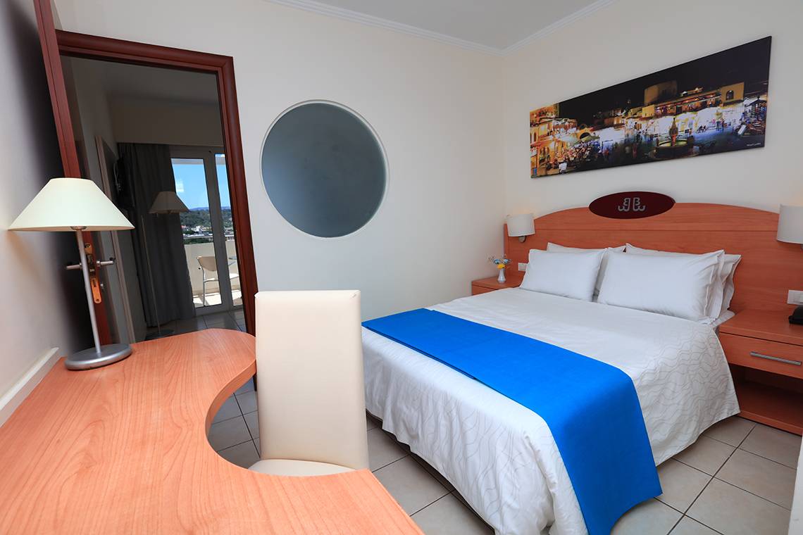 Ein modernes Zimmer im Blue Bay Beach Resort mit einem Bett, Schreibtisch und einem Stuhl.