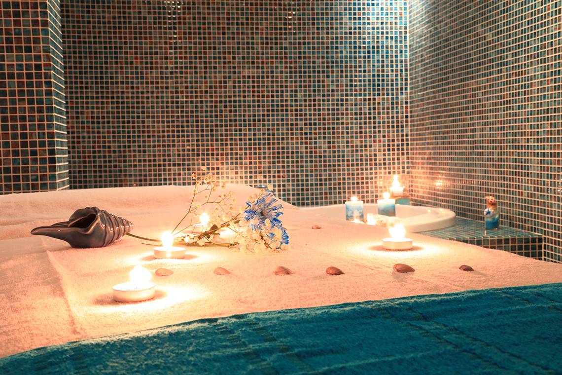 Spa-Behandlung im Blue Bay Beach Resort mit Kerzen und Blumen auf dem Bett.