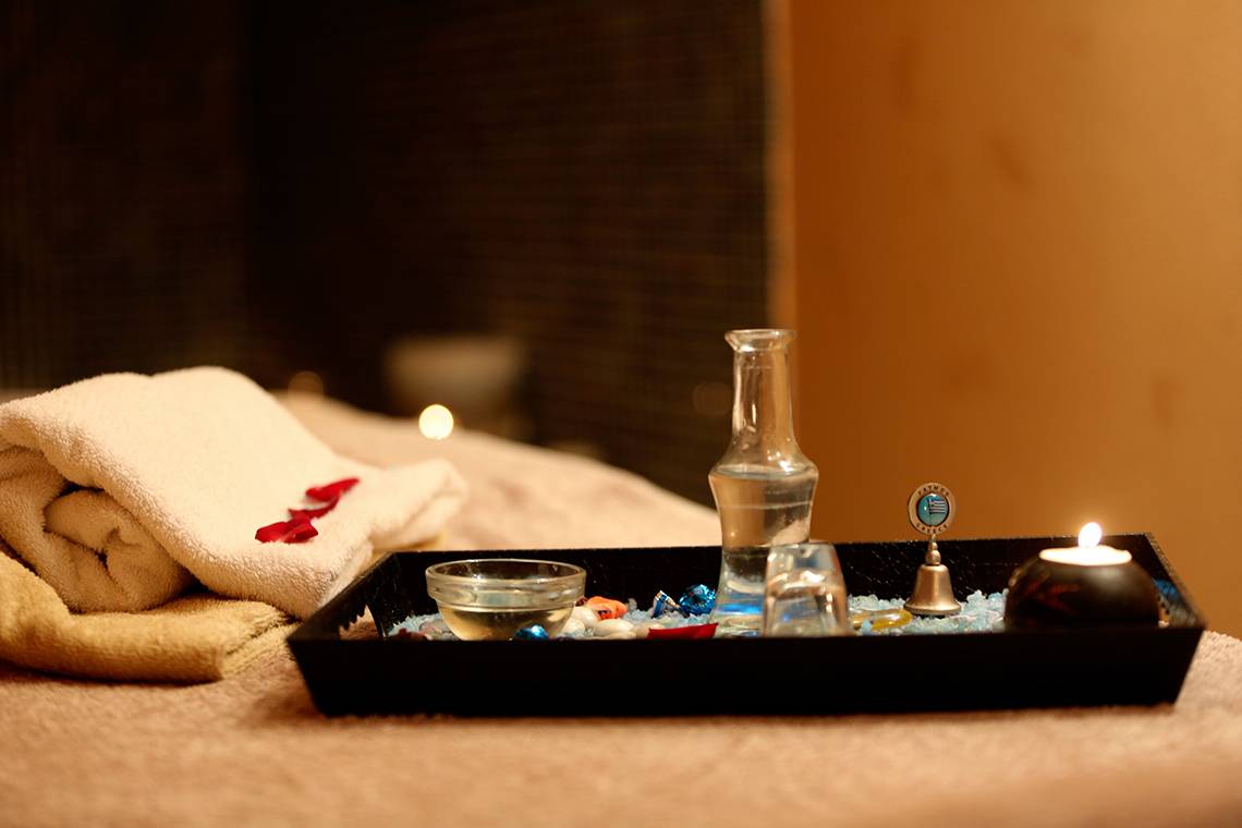 Spa-Angebot im Blue Bay Beach Resort mit Handtüchern, Kerzen und Accessoires auf einem Tablett.