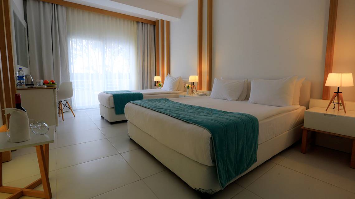Hotelzimmer im LABRANDA TMT Bodrum mit zwei Betten, weißer Bettwäsche, blauer Decke und modernen Möbeln.