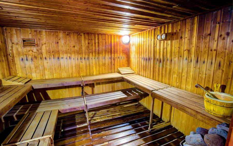 Sauna im SBH Club Paraiso Playa mit hölzernen Bänken und einer gelben Holzwanne.