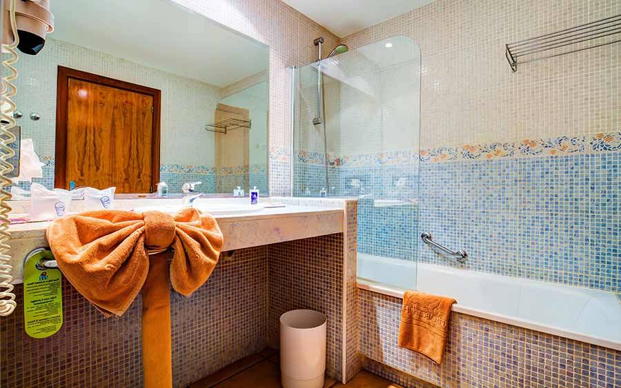 Badezimmer im SBH Club Paraiso Playa Hotel mit blauen Fliesen und Badewanne.