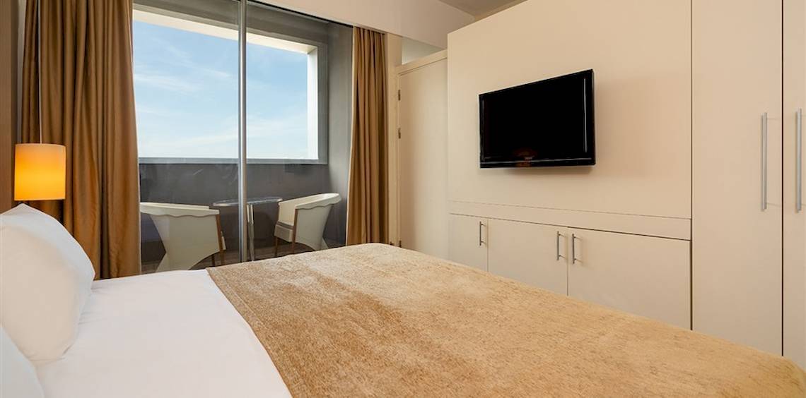 Hotelzimmer mit Bett, Fernseher und Balkon im Crystal Centro Resort.