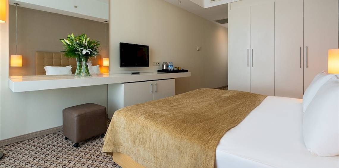 Ein modernes Hotelzimmer im Crystal Centro Resort mit Bett, Schreibtisch und Fernseher.