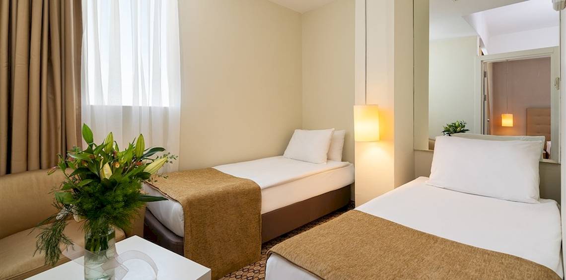 Doppelzimmer im Crystal Centro Resort mit zwei Betten, einem Tisch und einer Couch.
