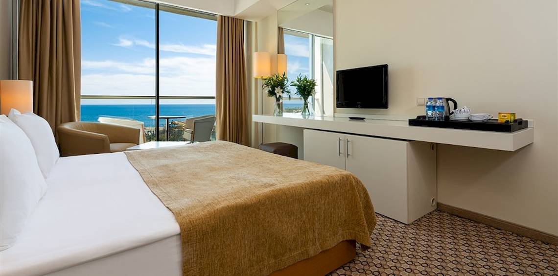 Hotelzimmer im Crystal Centro Resort mit Meerblick, einem großen Bett, Schreibtisch und Fernseher.